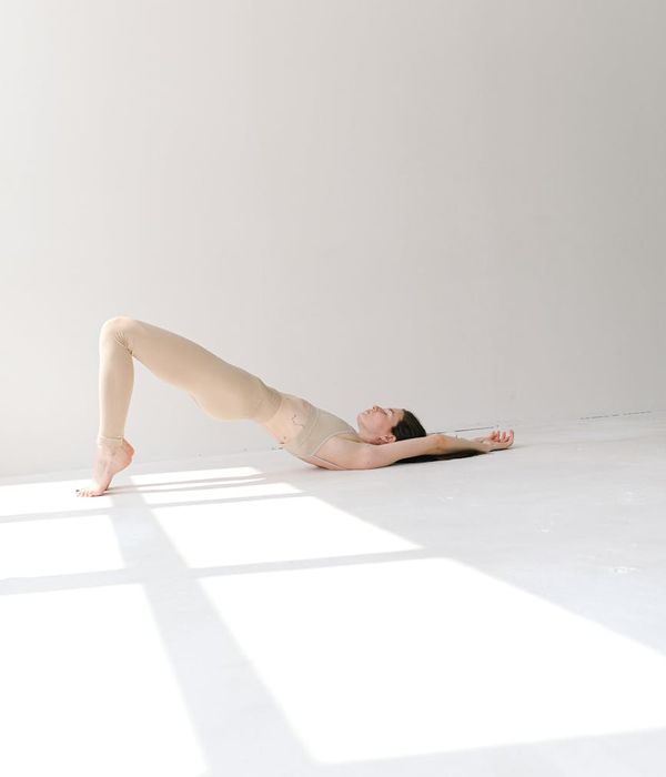 Woman in a calm yoga pose against a light lavender background.